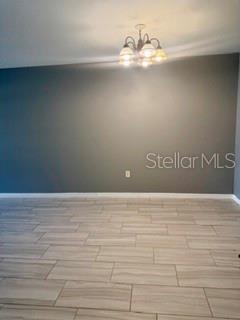 A room with light-colored wood-look tile flooring, a dark gray accent wall, and a chandelier — 22 PLATEAU LANE UNIT B, PALM COAST, FL