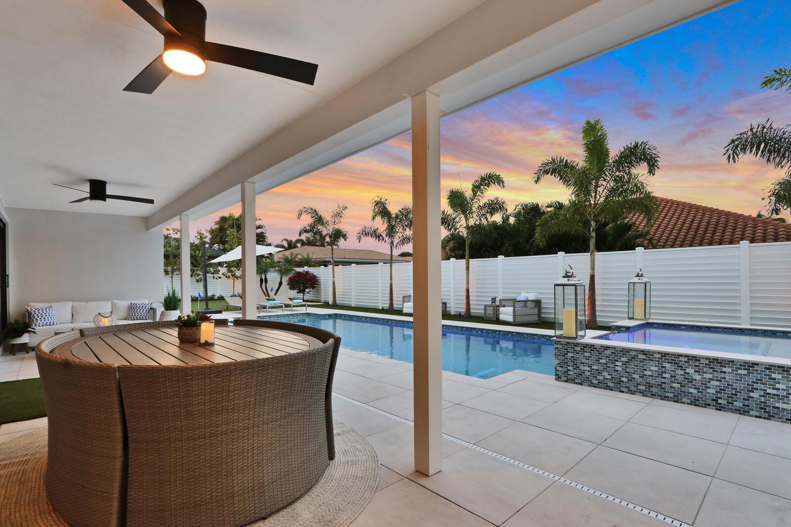 A covered patio features a dining set, ceiling fans, and a pool with a spa — 441 S Lyra Circle, Juno Beach FL 33408, JUNO BEACH, FL