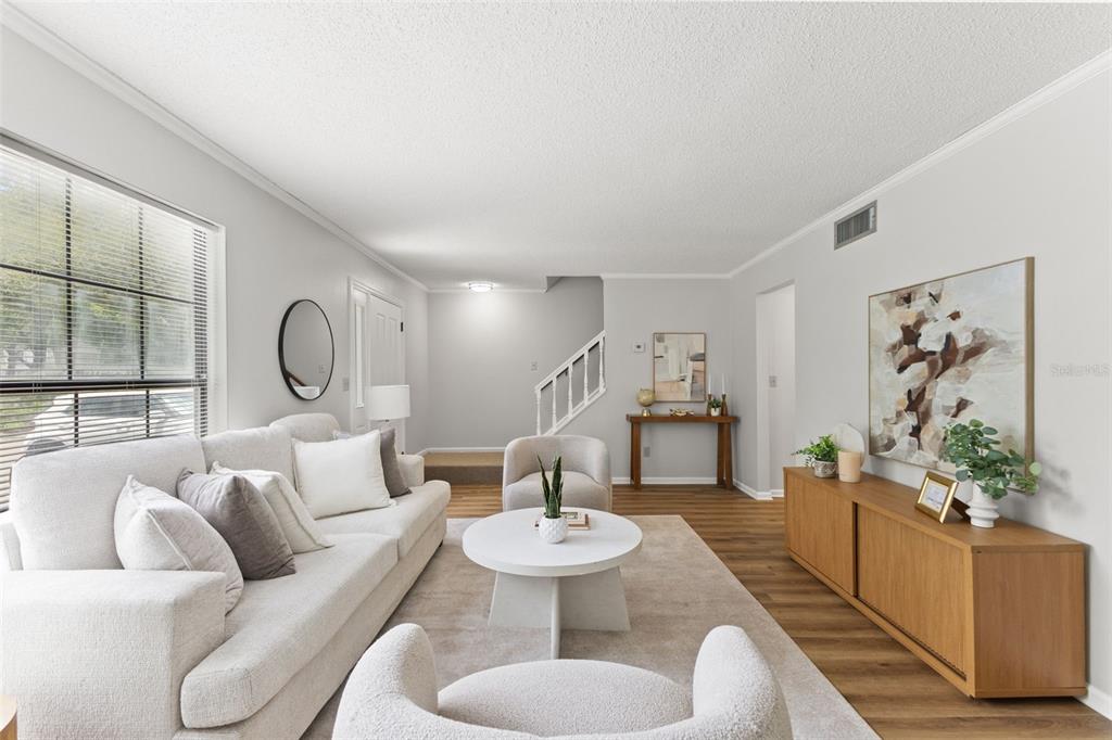 A bright living room features a white sofa, two armchairs, a round table, and wood flooring — 14809 WINDING CREEK COURT, TAMPA, FL
