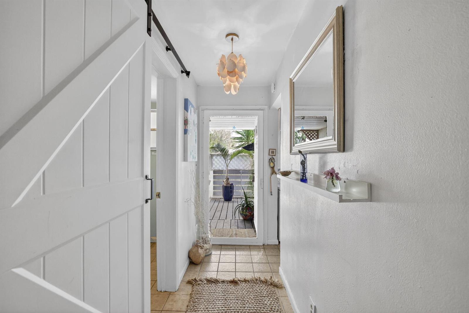 A bright hallway features a white barn door, tile flooring, and a glass door leading outside — 153 W Hemingway Circle W, Margate FL 33063, MARGATE, FL