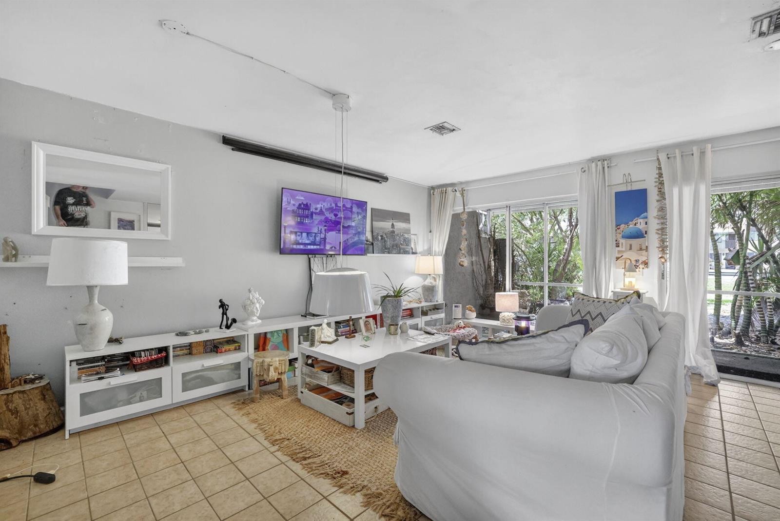A living room features a white sofa, a coffee table, media consoles, and tile flooring — 153 W Hemingway Circle W, Margate FL 33063, MARGATE, FL