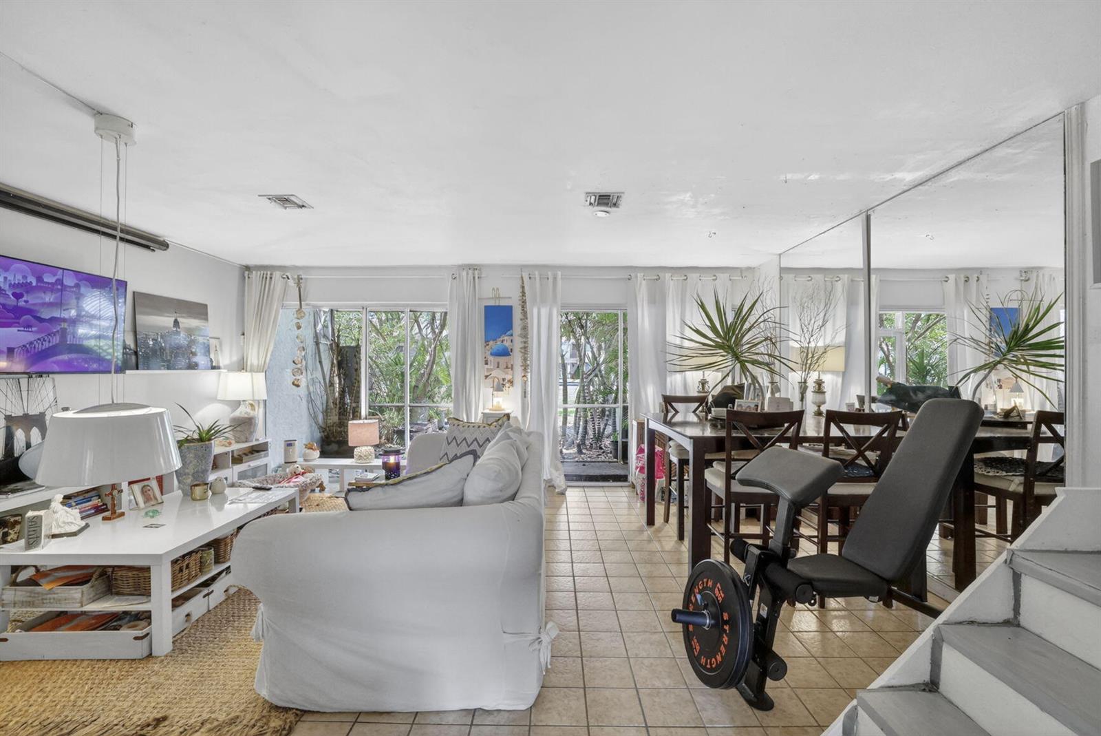 A living and dining room with tile floors, a white sofa, and a workout bench — 153 W Hemingway Circle W, Margate FL 33063, MARGATE, FL
