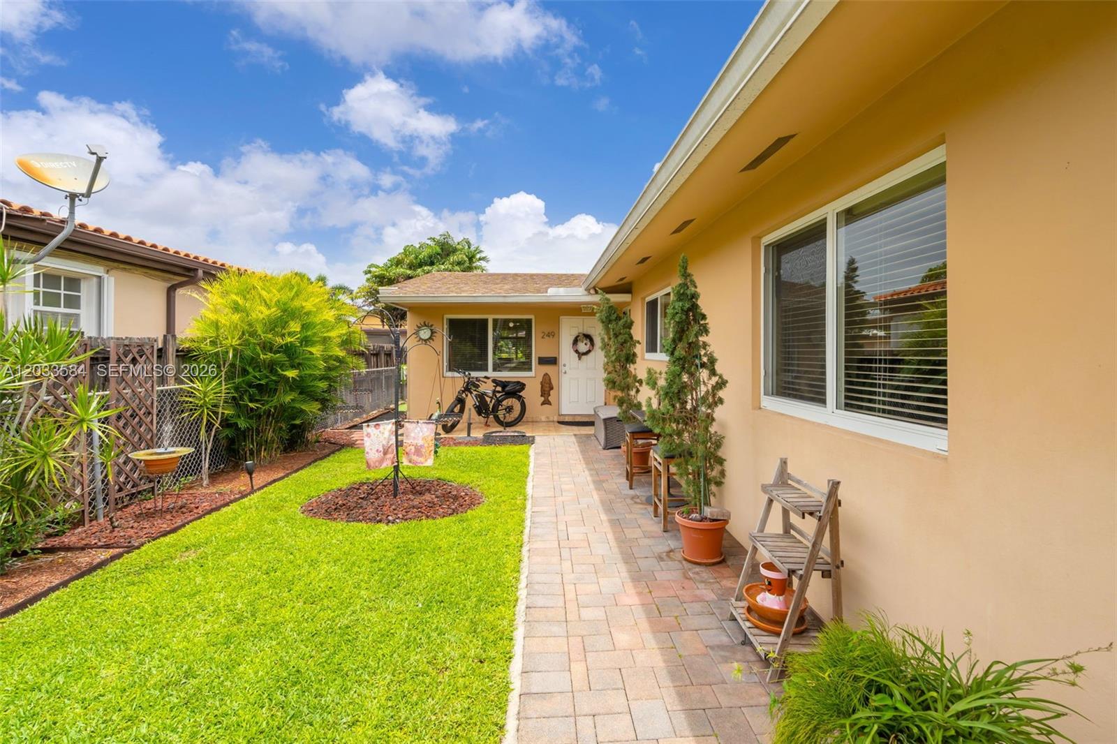 A paved walkway leads to the front entrance of a tan house with a lawn — 247 NW 51st Ave, Miami FL 33126, MIAMI, FL