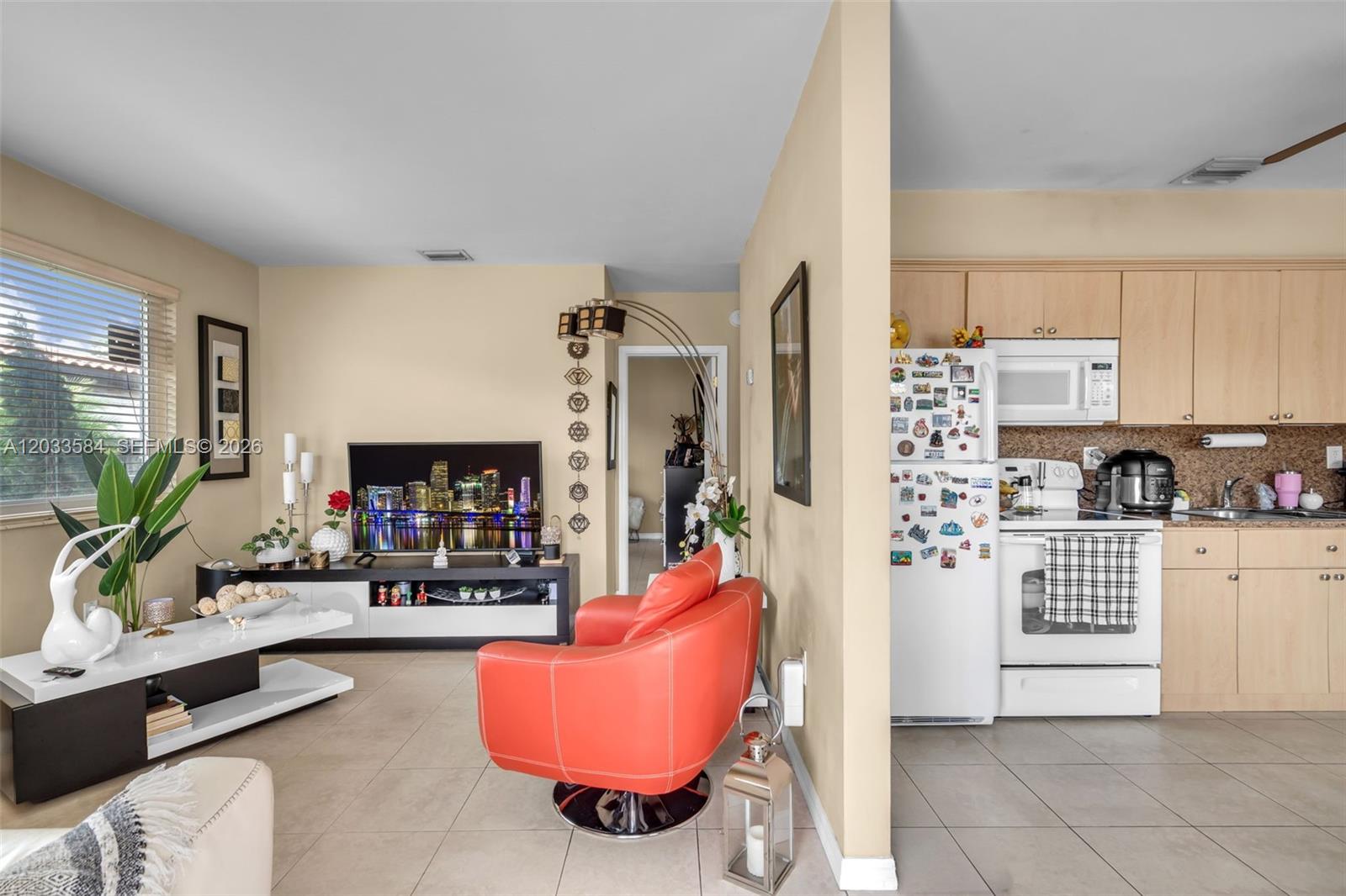 A living room with a red swivel chair opens into a kitchen with light-wood cabinets — 247 NW 51st Ave, Miami FL 33126, MIAMI, FL