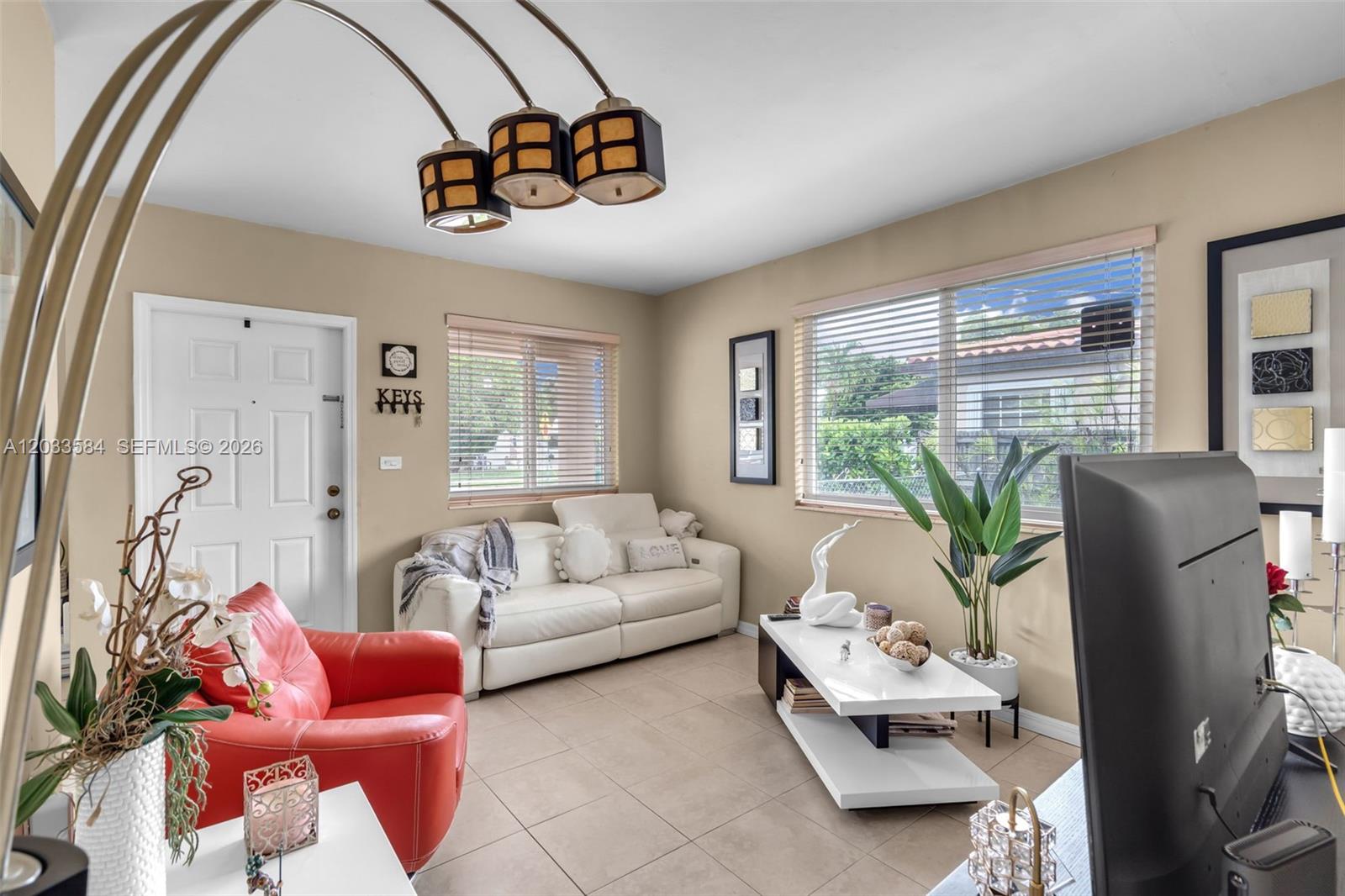 A living room features a white sofa, a red armchair, tile flooring, and a television — 247 NW 51st Ave, Miami FL 33126, MIAMI, FL