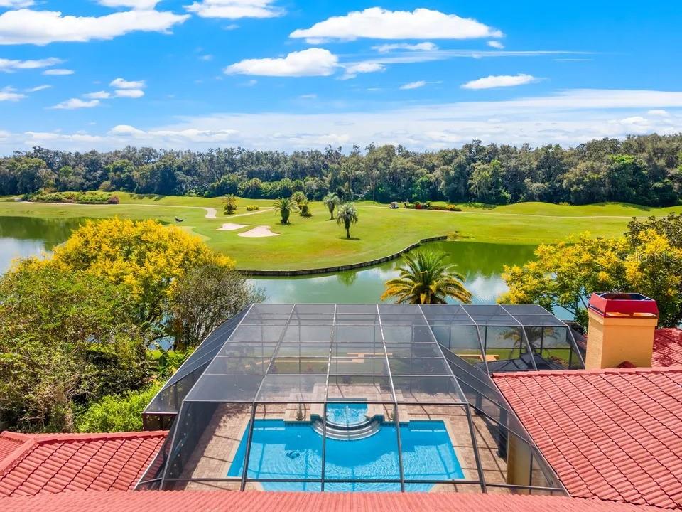 An elevated view of a screened-in pool and patio overlooking a golf course and lake — 30324 LAURELWOOD LANE, WESLEY CHAPEL, FL