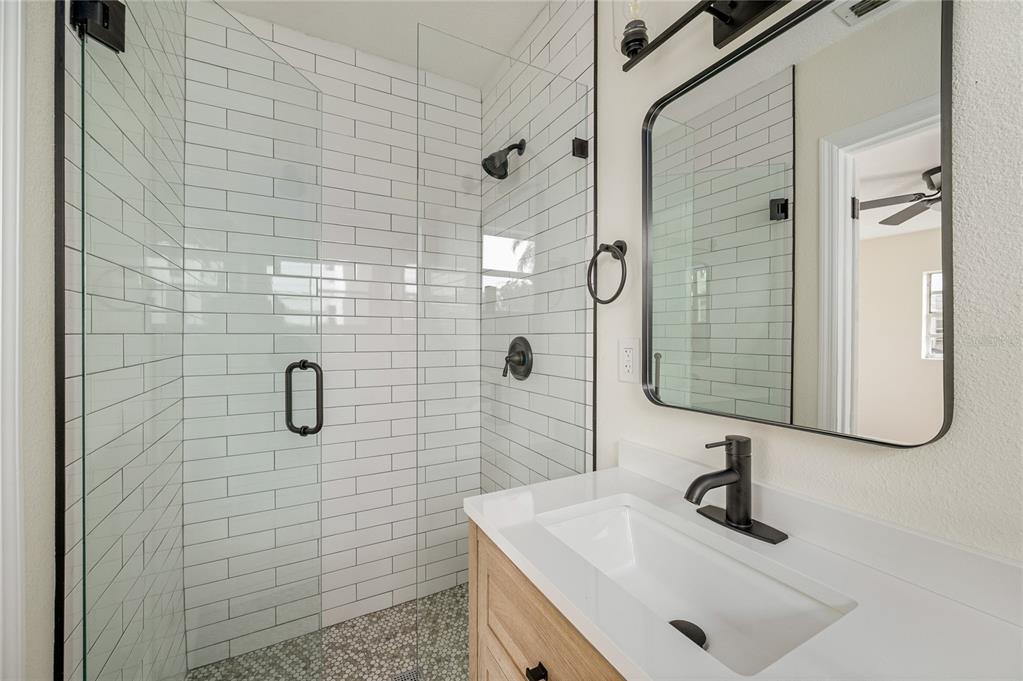 A bathroom features a glass-enclosed shower with white subway tile and a wood vanity — 3733 SURREY DRIVE, ORLANDO, FL