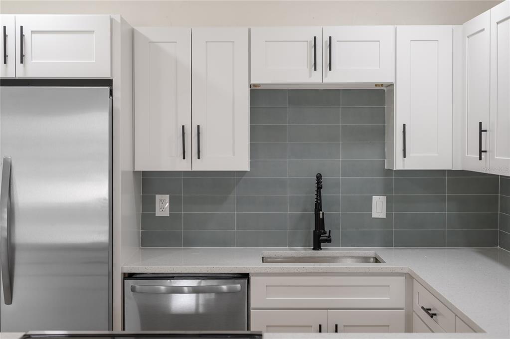 A kitchen features white shaker cabinets, a gray tiled backsplash, stainless steel appliances, and countertops — 3733 SURREY DRIVE, ORLANDO, FL