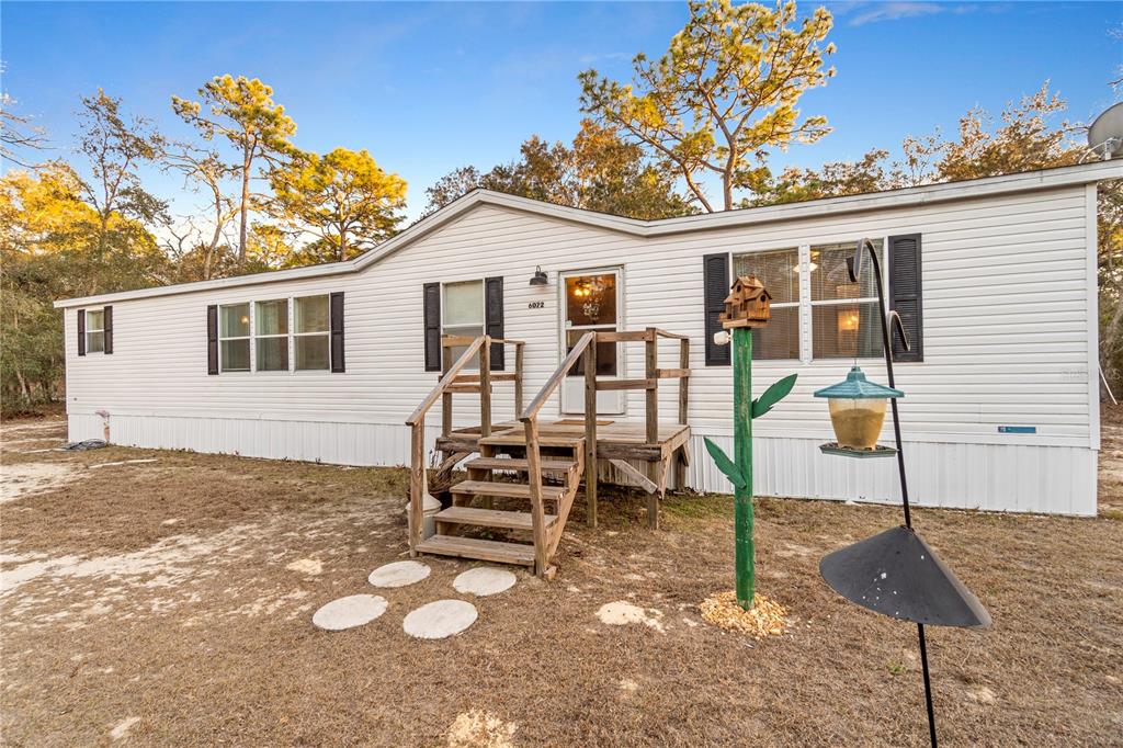 A single-story manufactured home with white siding and a wooden front porch — 6072 W PATRIOT STREET, HOMOSASSA, FL