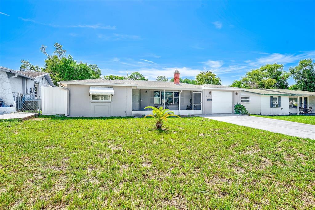 A single-story house with a grey exterior, a brick chimney, and a front lawn — 5126 ROSEWOOD DRIVE, NEW PORT RICHEY, FL