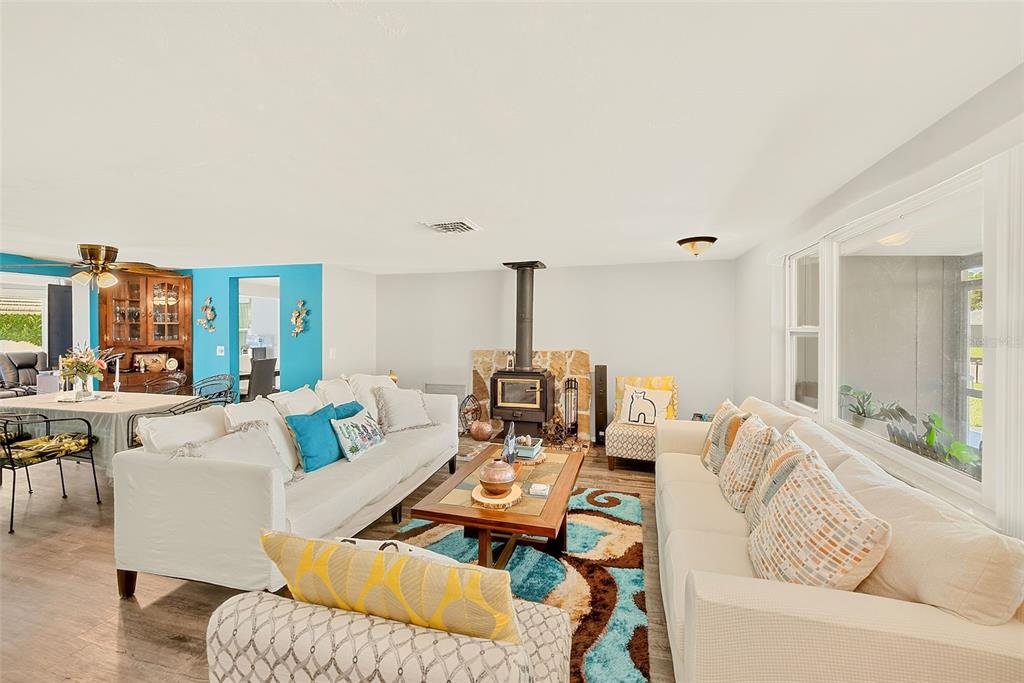 A living room features a wood-burning stove, white sofas, and a colorful patterned area rug — 5126 ROSEWOOD DRIVE, NEW PORT RICHEY, FL