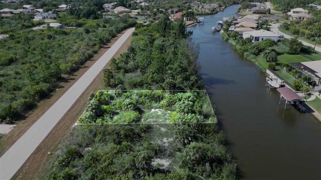 An aerial view shows a vacant, rectangular lot bordered by a paved path and a canal — 15480 ARIBE AVENUE, PORT CHARLOTTE, FL