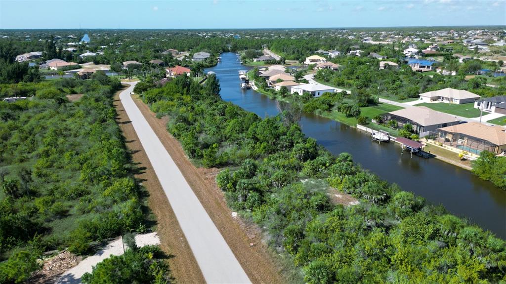 An aerial view shows a canal running between residential homes and a paved road — 15480 ARIBE AVENUE, PORT CHARLOTTE, FL