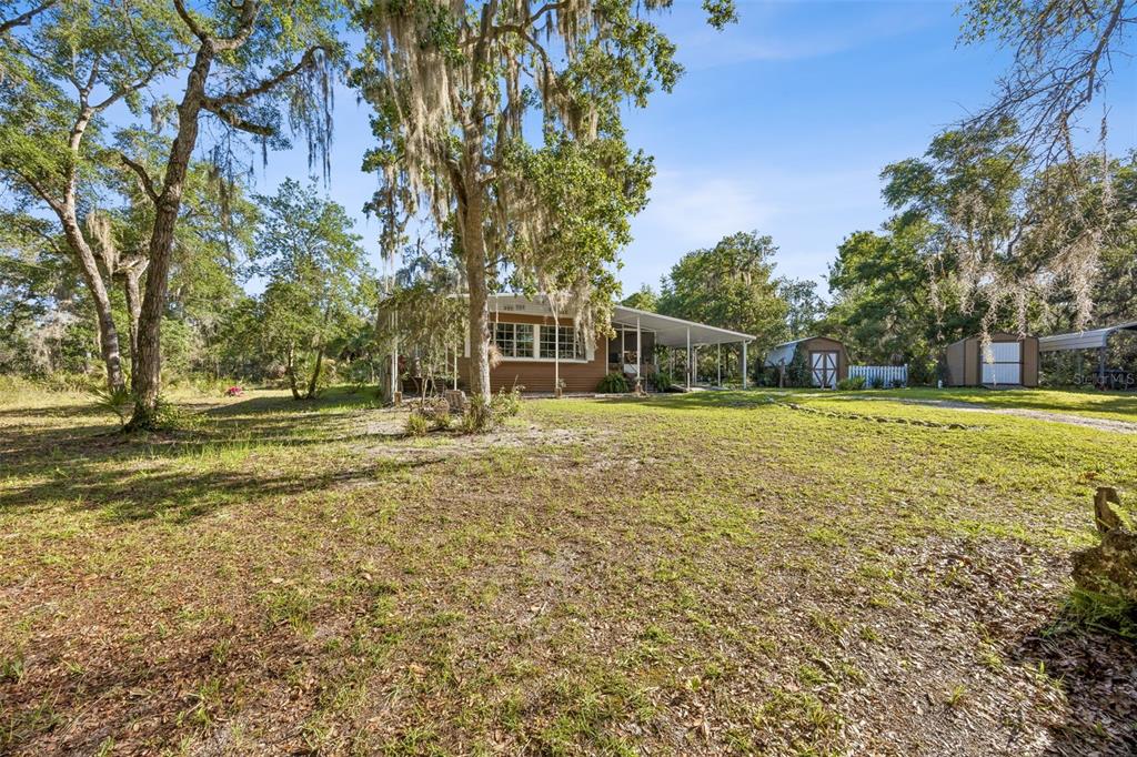 A single-story house with a covered porch sits on a grassy lot with mature trees — 110 PLUMOSA DRIVE, GEORGETOWN, FL