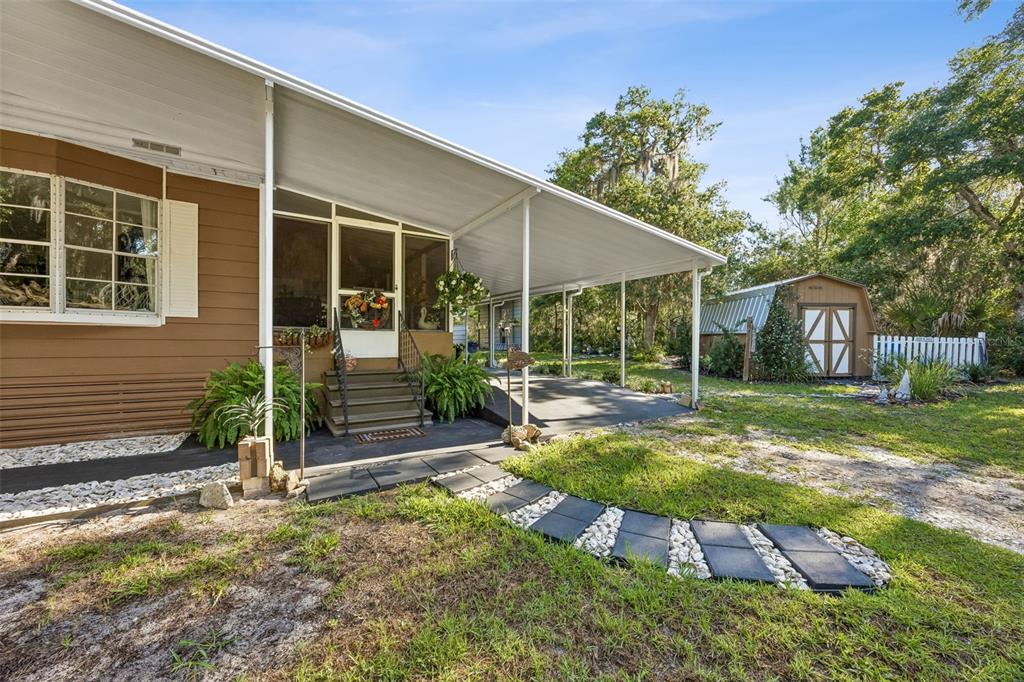 A tan mobile home with a screened porch, carport, and a small shed in the yard — 110 PLUMOSA DRIVE, GEORGETOWN, FL