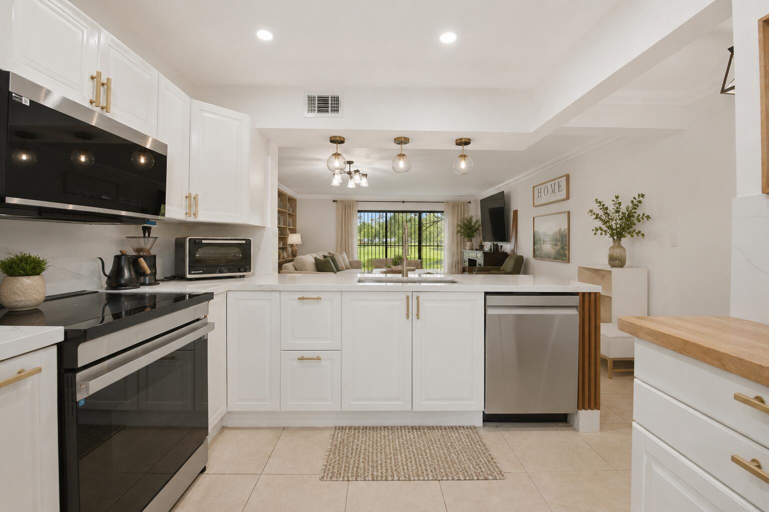 A white kitchen with gold hardware and stainless steel appliances opens into a living room — 371 W Park Drive # 17, Miami FL 33172, MIAMI, FL