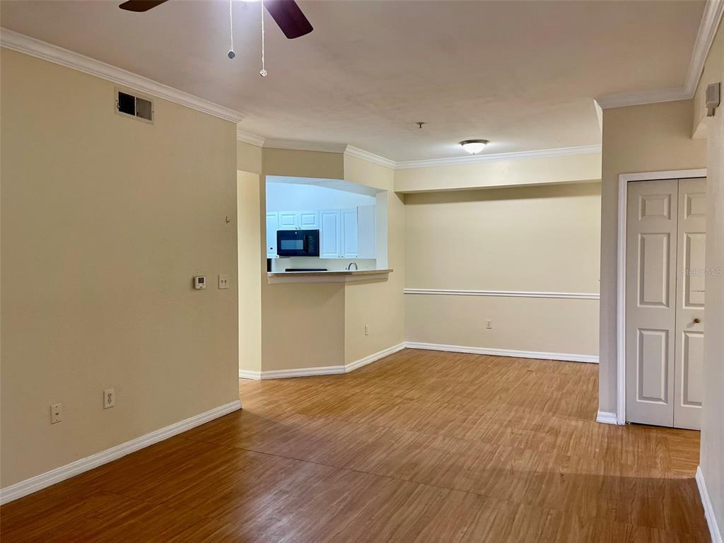 An interior view of a living room with wood-look flooring and an open kitchen pass-through — 5550 P G A BOULEVARD UNIT 5126, ORLANDO, FL