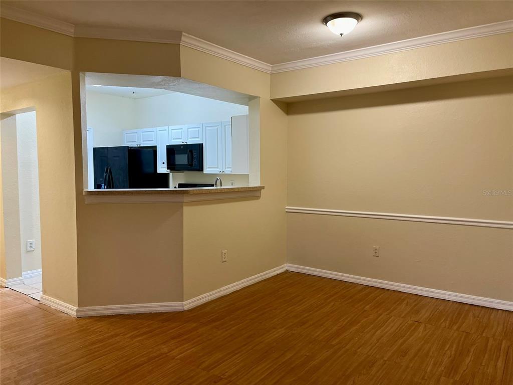 A dining area with wood-look flooring features a pass-through window looking into the kitchen — 5550 P G A BOULEVARD UNIT 5126, ORLANDO, FL