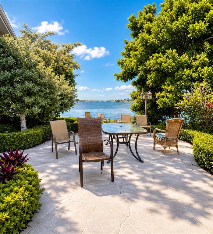 A patio with a glass-top table and chairs overlooks a body of water — 295 110TH AVENUE UNIT 1, ST PETERSBURG, FL