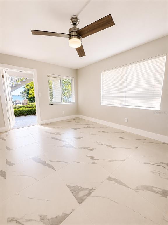 A room with white marble-look tile flooring, a ceiling fan, and a view of water — 295 110TH AVENUE UNIT 1, ST PETERSBURG, FL