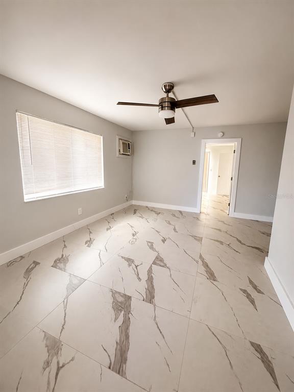 A room with light gray walls, a ceiling fan, and large white marble-patterned floor tiles — 295 110TH AVENUE UNIT 1, ST PETERSBURG, FL