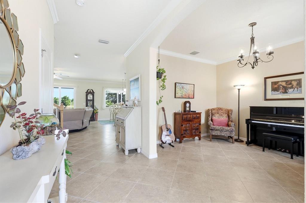 A tiled entryway leads to a living area with a piano, armchair, and guitar — 12541 CINQUETERRE DRIVE, VENICE, FL