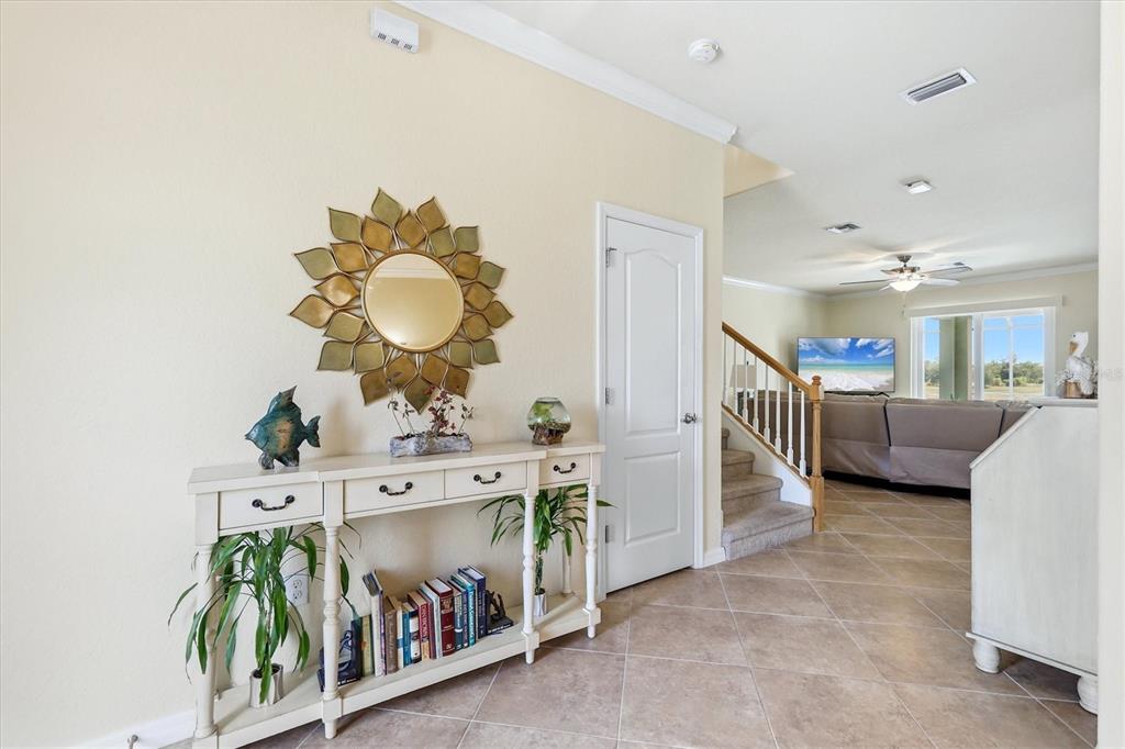 An entryway features a console table with books and decor below a sunburst wall mirror — 12541 CINQUETERRE DRIVE, VENICE, FL