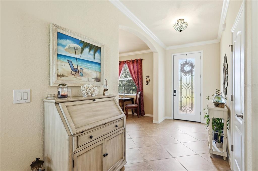 An entryway features tile flooring, a wooden secretary desk, and a glass-paneled front door — 12541 CINQUETERRE DRIVE, VENICE, FL