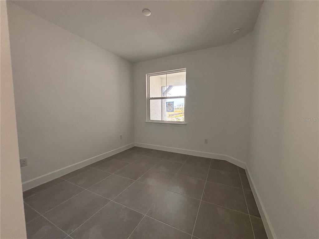 A paved walkway leads to the front entrance of a house with white stucco walls — 1596 TAVIRA PLACE, ENGLEWOOD, FL
