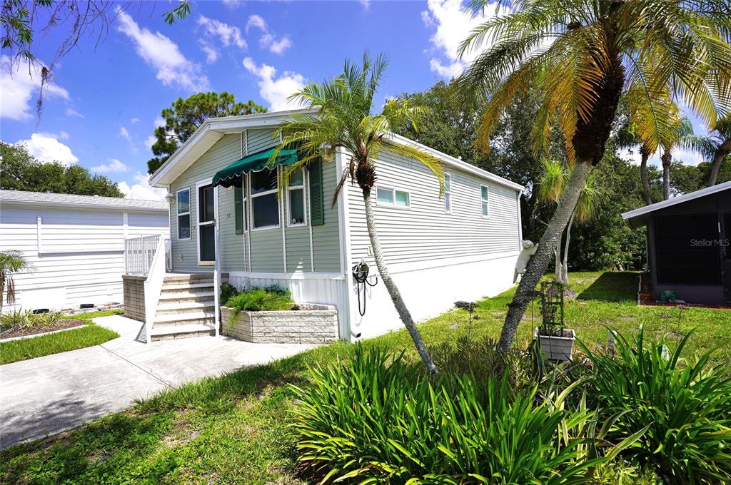 A light green mobile home with a white staircase and palm trees in the yard — 125 BROOKSHIRE DRIVE, NOKOMIS, FL
