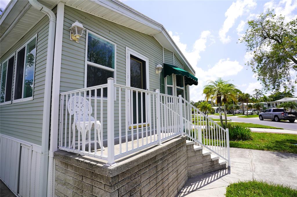 A light green mobile home features a concrete porch with white railings and stairs — 125 BROOKSHIRE DRIVE, NOKOMIS, FL