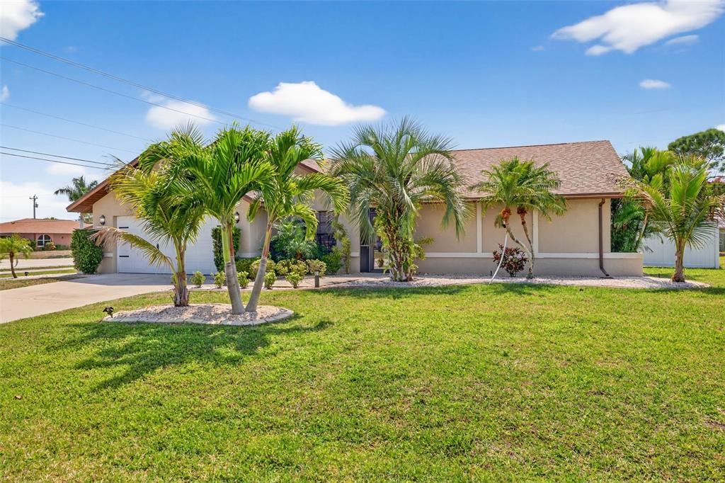 A single-story house with a tan exterior, a shingled roof, and palm trees in front — 402 SW 37TH LANE, CAPE CORAL, FL