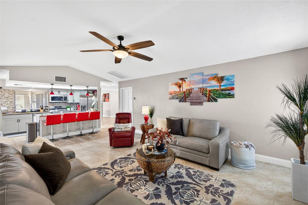 A living room with a gray sofa, red recliner, and an open kitchen with bar stools — 402 SW 37TH LANE, CAPE CORAL, FL