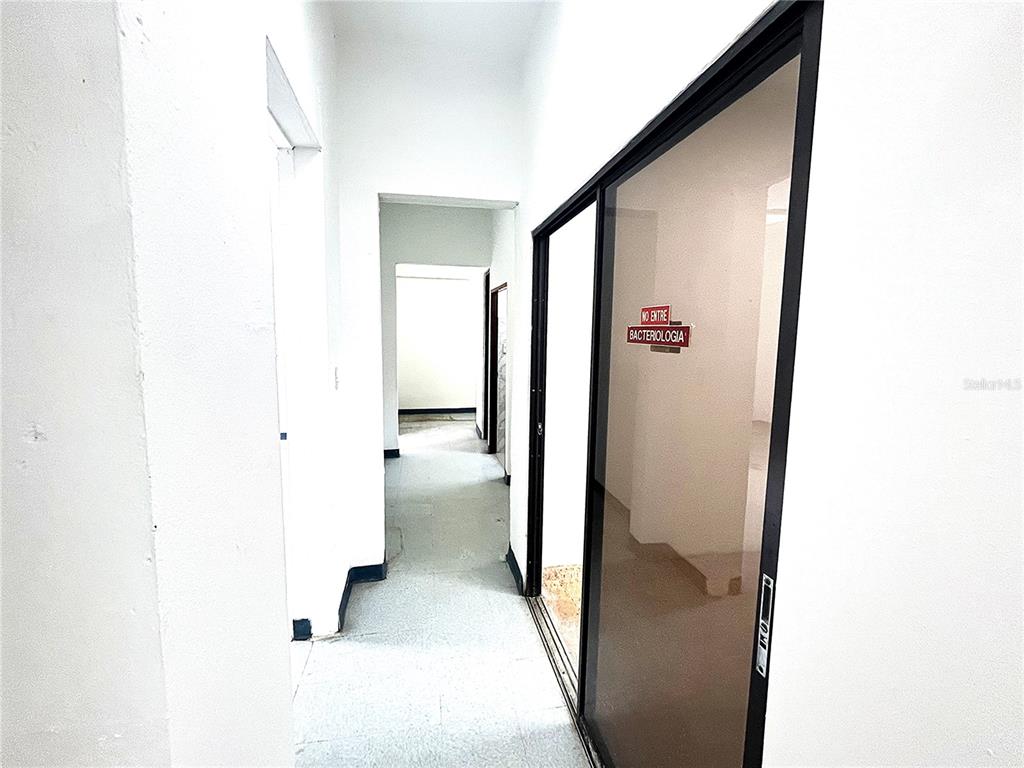 A hallway with white walls and tile flooring leads to a room labeled Bacteriologia — 757 HIPODROMO, SAN JUAN, PR