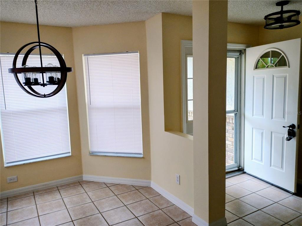 A tiled entryway and dining area feature a spherical chandelier, large windows, and a front door — 9013 SW 91ST CIRCLE, OCALA, FL