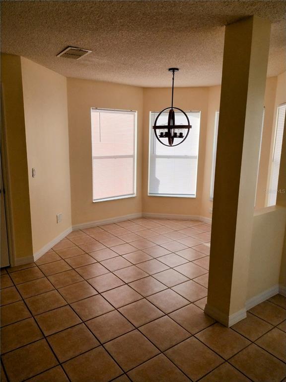 A dining area features tan tile flooring, light-colored walls, and a spherical chandelier — 9013 SW 91ST CIRCLE, OCALA, FL