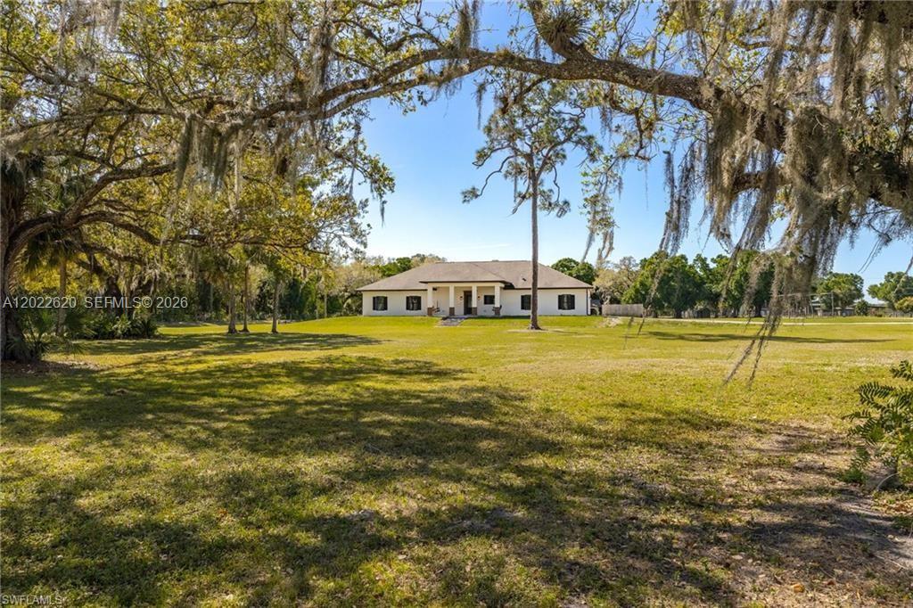 A single-story house sits in the distance behind a large, grassy yard with trees — 5535 COUNTY ROAD 78, La Belle FL 33935, LA BELLE, FL