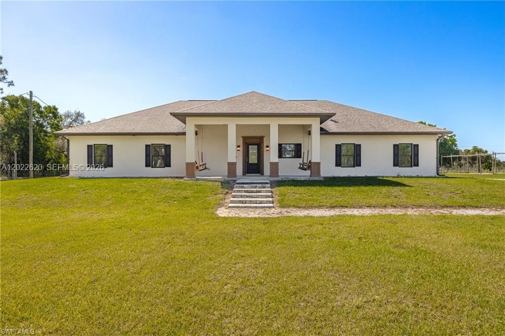 A single-story house with a covered porch, front door, and symmetrical windows sits on grass — 5535 COUNTY ROAD 78, La Belle FL 33935, LA BELLE, FL