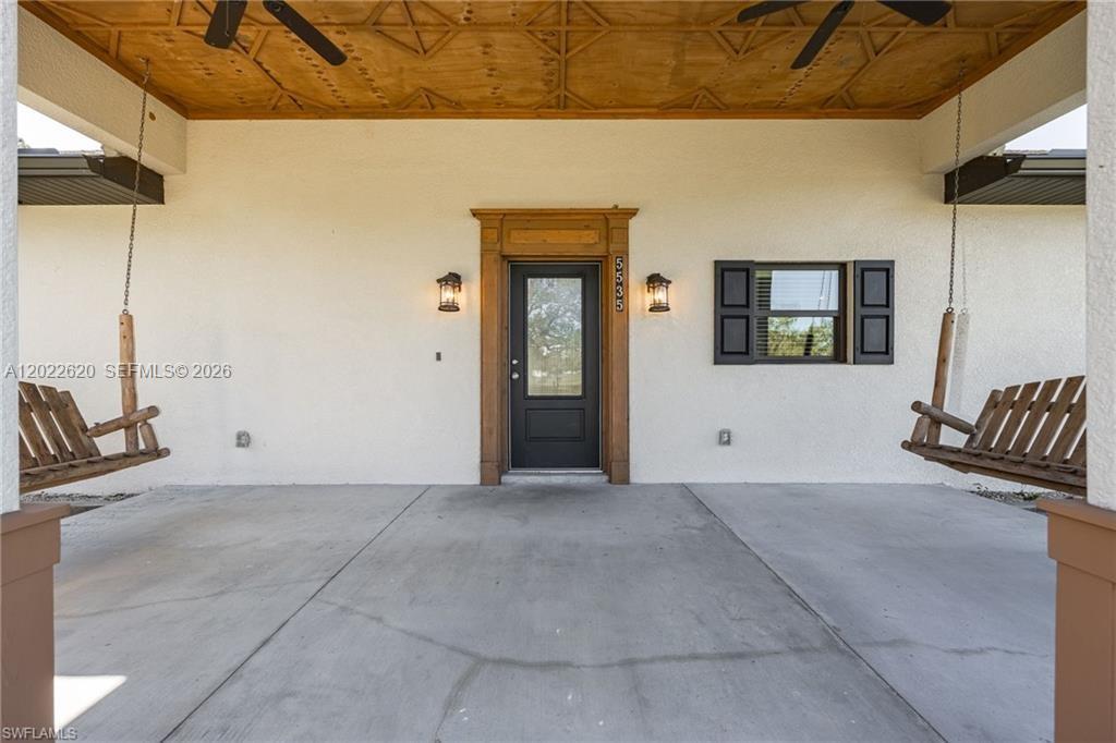 A covered front porch features a wooden ceiling, two hanging swings, and a central door — 5535 COUNTY ROAD 78, La Belle FL 33935, LA BELLE, FL