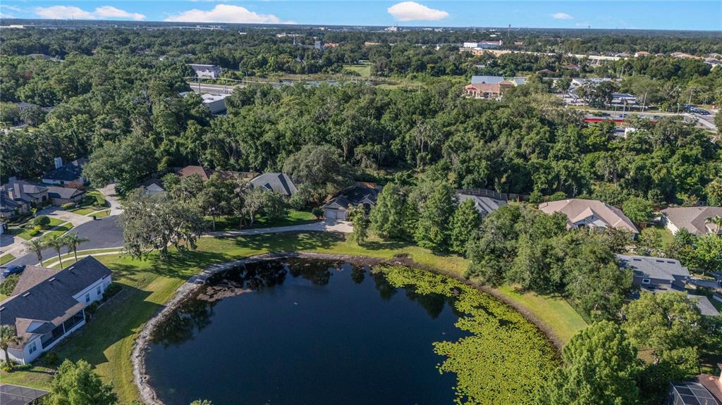An aerial view shows several houses surrounding a circular pond with lily pads — 177 OVEROAKS PLACE, SANFORD, FL