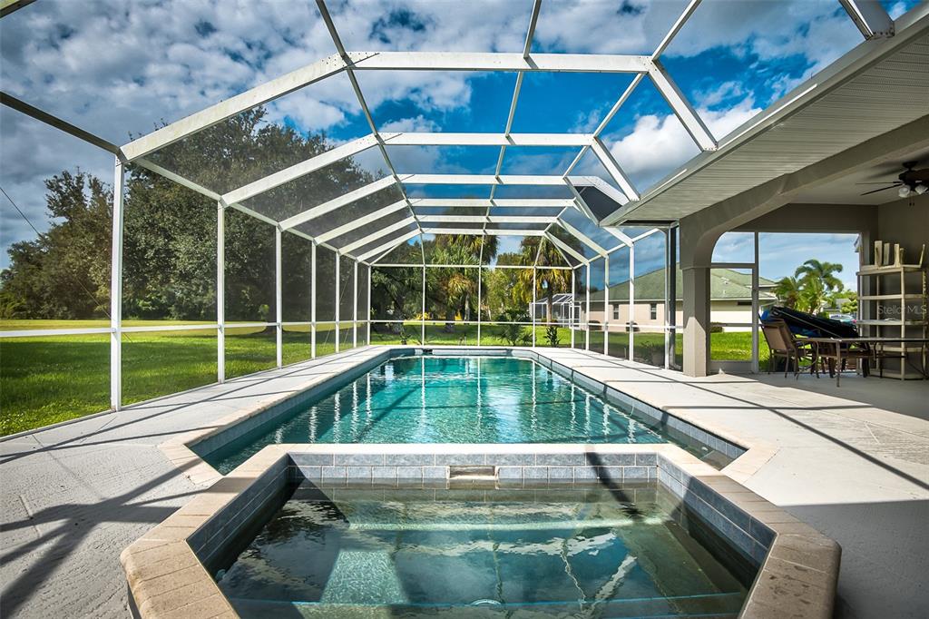 A screened-in swimming pool and hot tub sit on a patio overlooking a grassy yard — 27406 TIERRA DEL FUEGO CIRCLE, PUNTA GORDA, FL