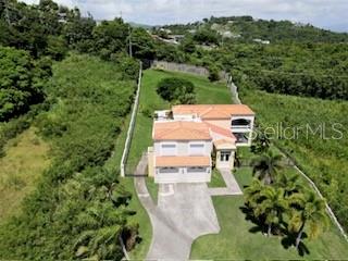 An aerial view shows a two-story house with a tiled roof surrounded by lush greenery — 53 HARBOUR LIGHTS, HUMACAO, PR