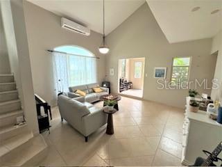 A living room with vaulted ceilings, tile floors, a gray sofa, and a staircase — 53 HARBOUR LIGHTS, HUMACAO, PR