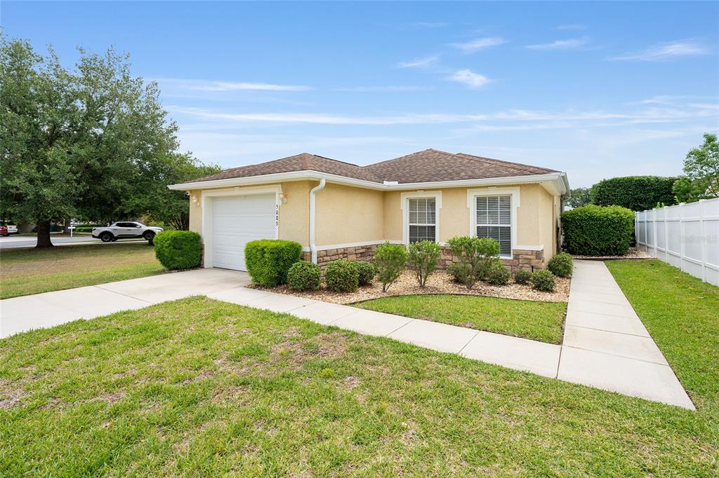 A single-story house with a tan stucco exterior, stone accents, and a one-car garage — 5085 NE 122ND BOULEVARD, OXFORD, FL