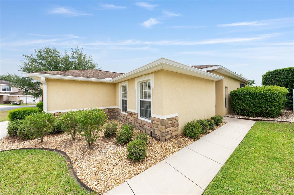 A tan stucco house with stone accents, a gravel garden, and a concrete walkway — 5085 NE 122ND BOULEVARD, OXFORD, FL