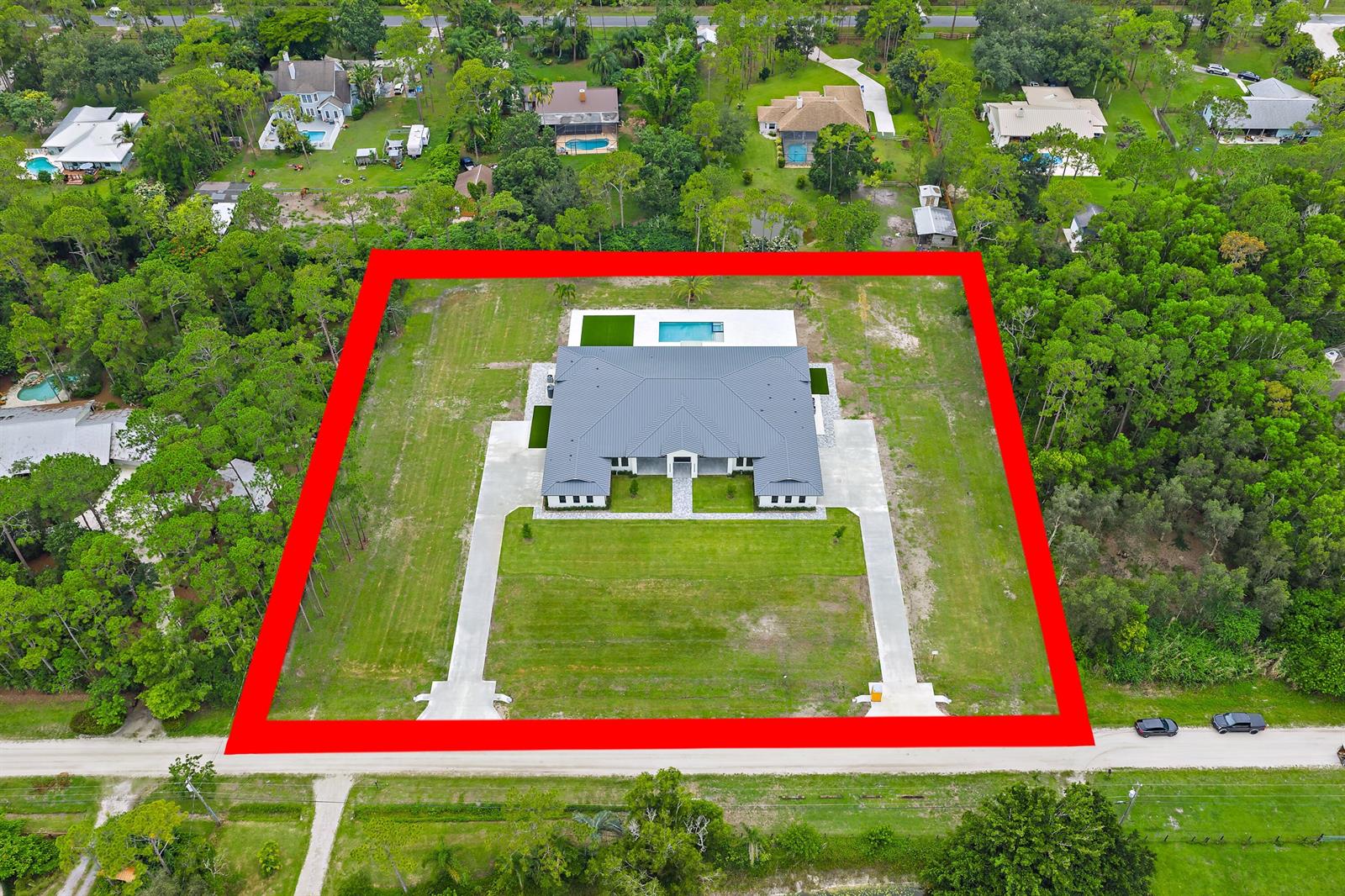 An aerial view shows a modern house with a pool on a large, grassy lot — 12850 152nd Street N, Jupiter FL 33478, JUPITER, FL