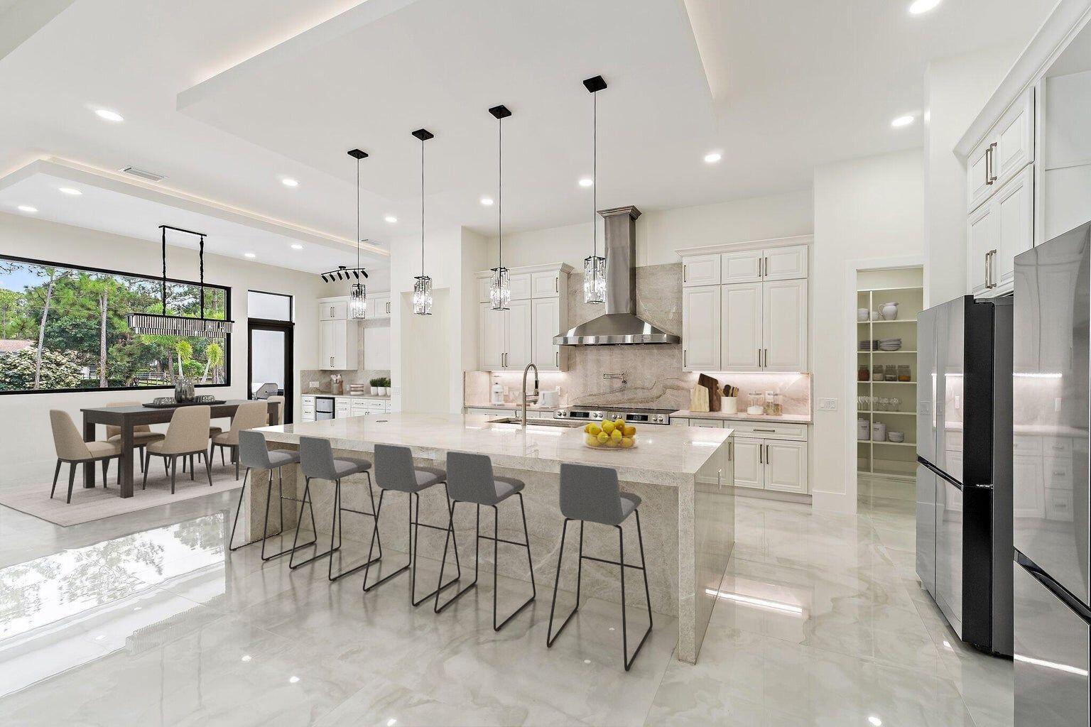 A modern kitchen features a large stone island, white cabinetry, and a dining area nearby — 12850 152nd Street N, Jupiter FL 33478, JUPITER, FL