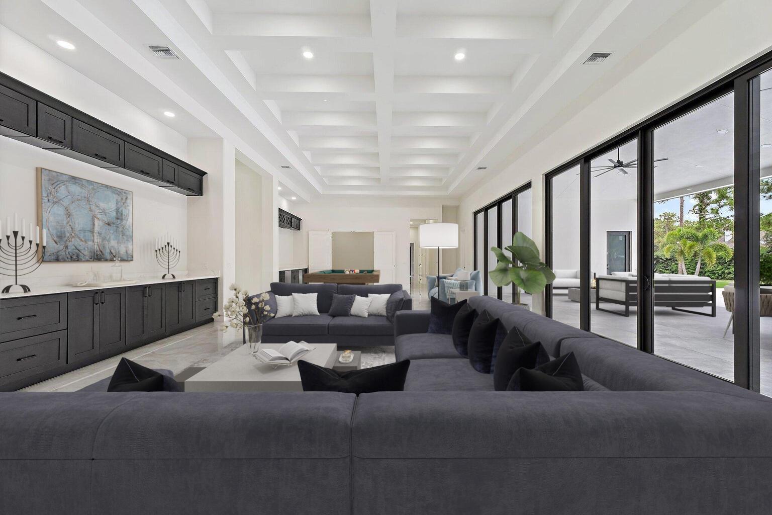 A spacious living room features a coffered ceiling, dark cabinetry, and large sliding glass doors — 12850 152nd Street N, Jupiter FL 33478, JUPITER, FL