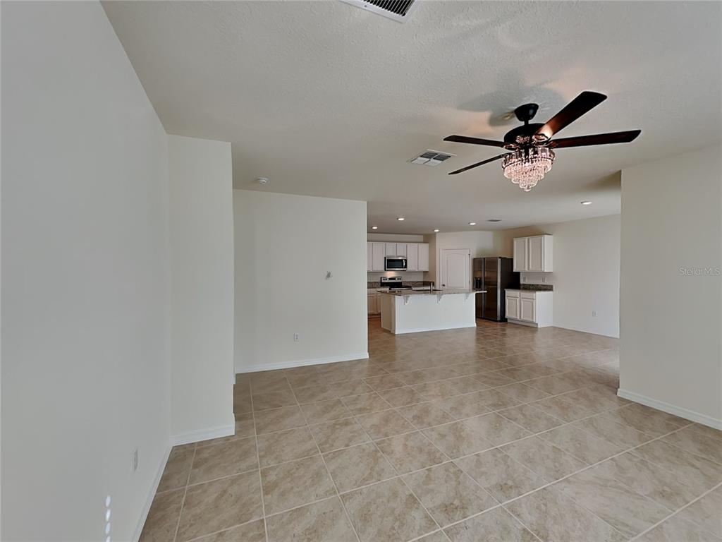 An open-concept living area features tile flooring, a ceiling fan, and a kitchen with white cabinetry — 1004 BROOKLET DRIVE, DAVENPORT, FL
