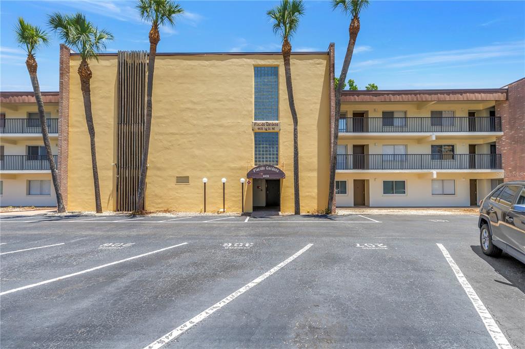 A three-story apartment building with a yellow facade and palm trees in the parking lot — 4435 1ST STREET NE UNIT 104, ST PETERSBURG, FL